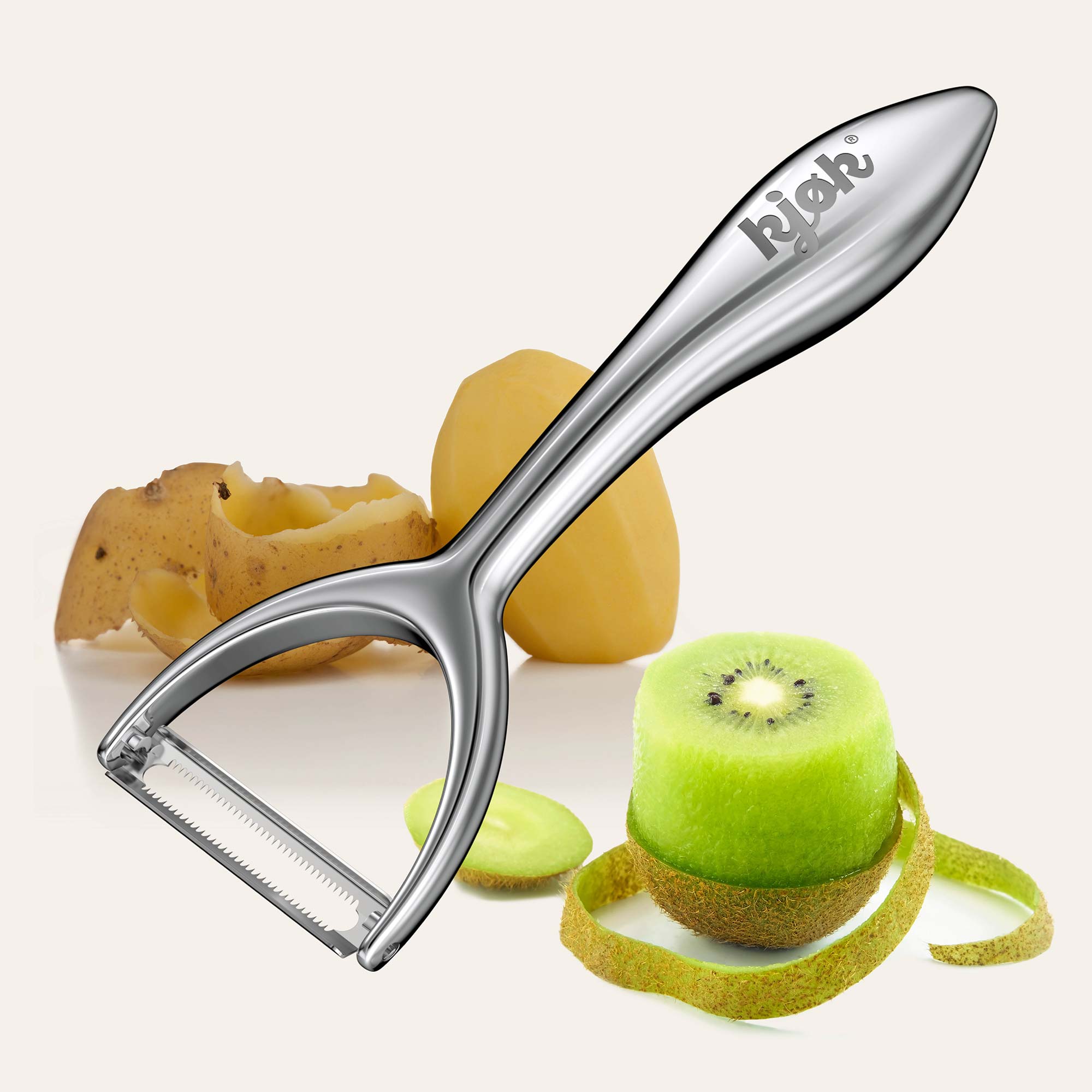 Der kjøk Sparschäler aus Edelstahl beim Schälen von Kartoffeln und Kiwi – scharf, elegant und für jede Schale geeignet