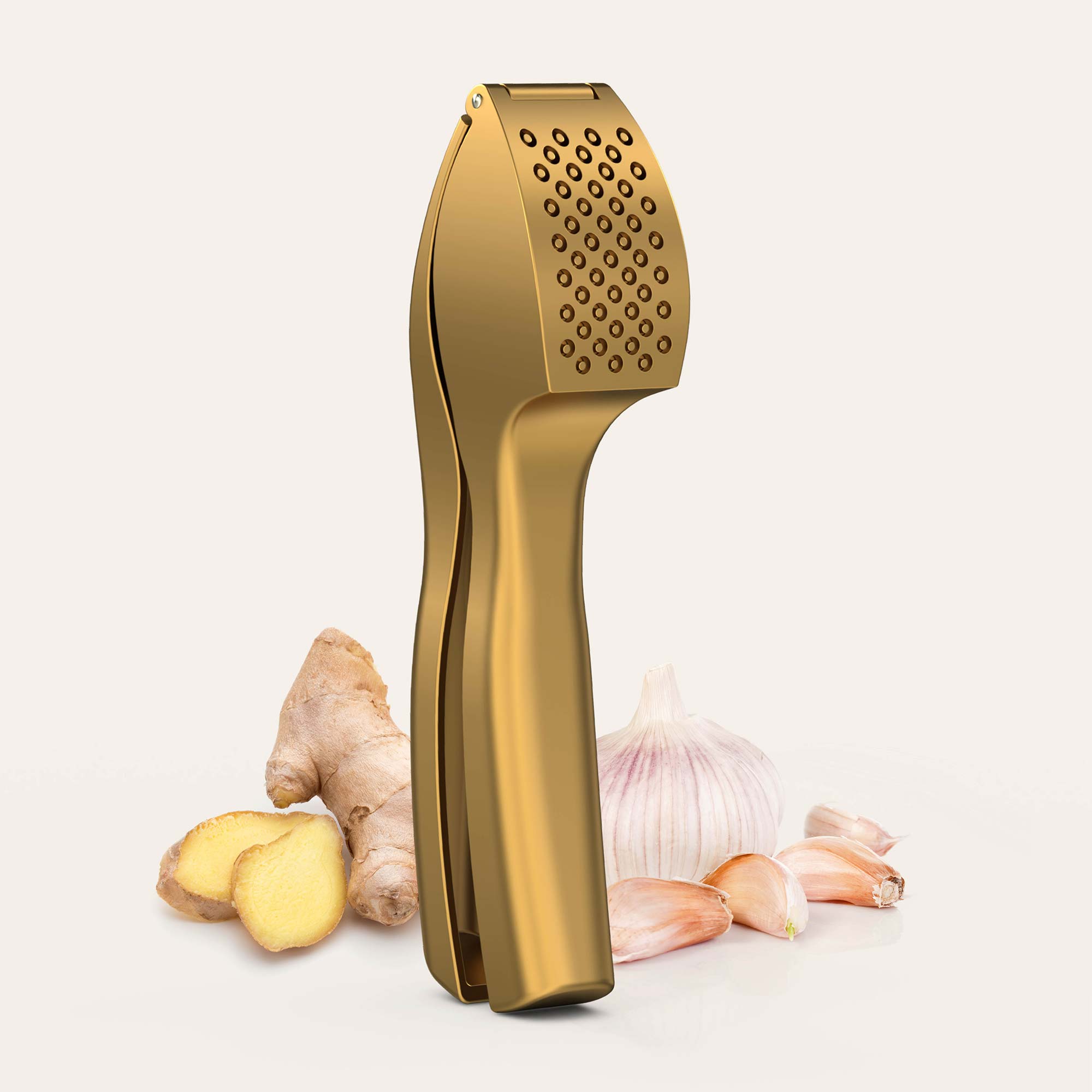 Goldene Knoblauchpresse auf hellem Hintergrund mit frischem Ingwer und Knoblauch