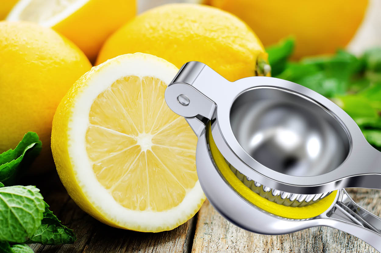 Zitronenpresse von kjøk neben frischer, aufgeschnittener Zitrone und Minzblättern auf rustikalem Holztisch