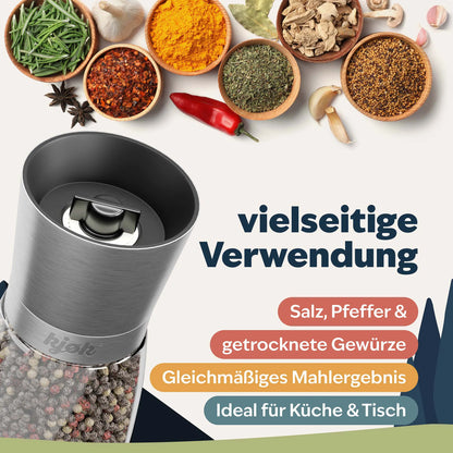 Salz- und Pfeffermühle vor verschiedenen Gewürzen wie Pfeffer, Kräutern und Chili